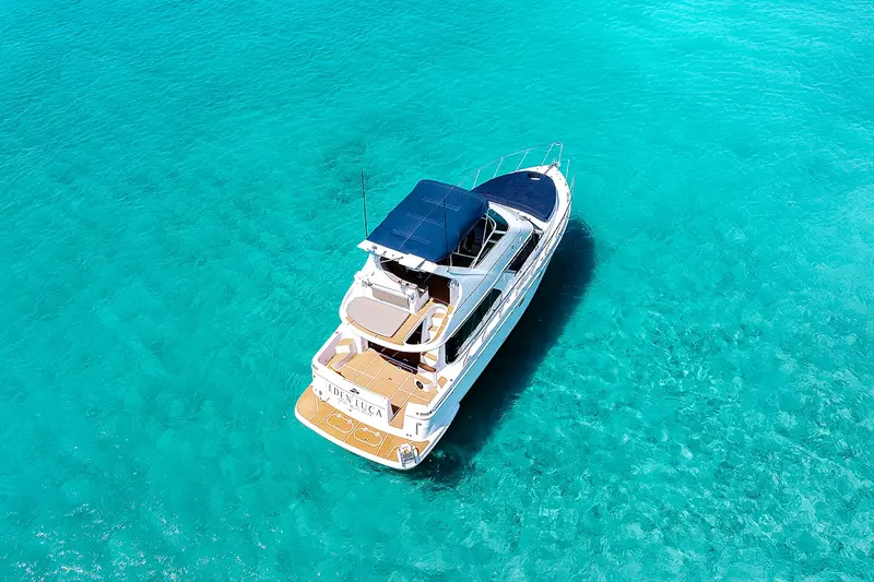 Eden Luca Blue from above in turquoise water off Aruba, with her navy bow lounge and teak aft deck