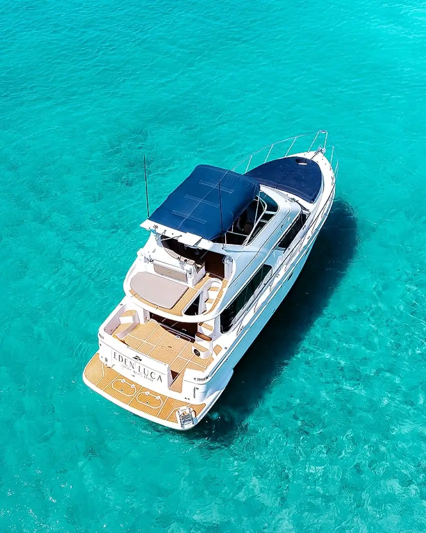 Eden Luca Blue visto de cima em águas turquesa de Aruba, com o solário de proa azul-marinho e o deck de popa em teca