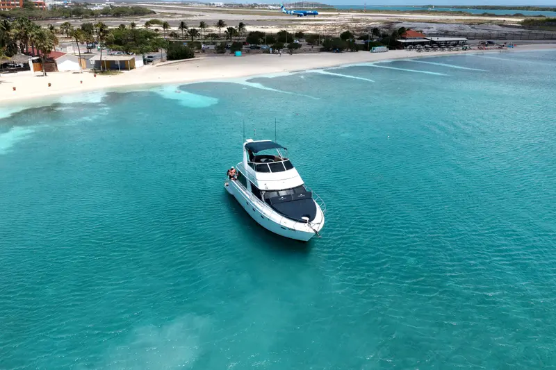 Eden Luca Blue anchored in clear shallows off a white-sand Aruba beach