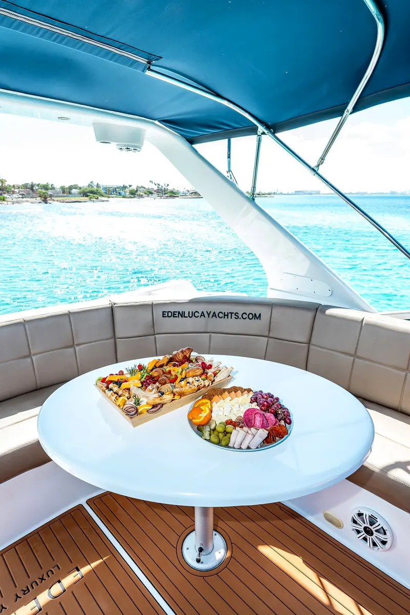 Charcuterie and fresh fruit platters on the shaded flybridge table of Eden Luca Blue