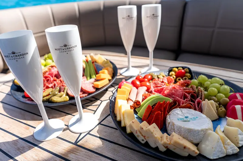 Charcuterie and cheese platters with flutes on the teak table of an Eden Luca yacht