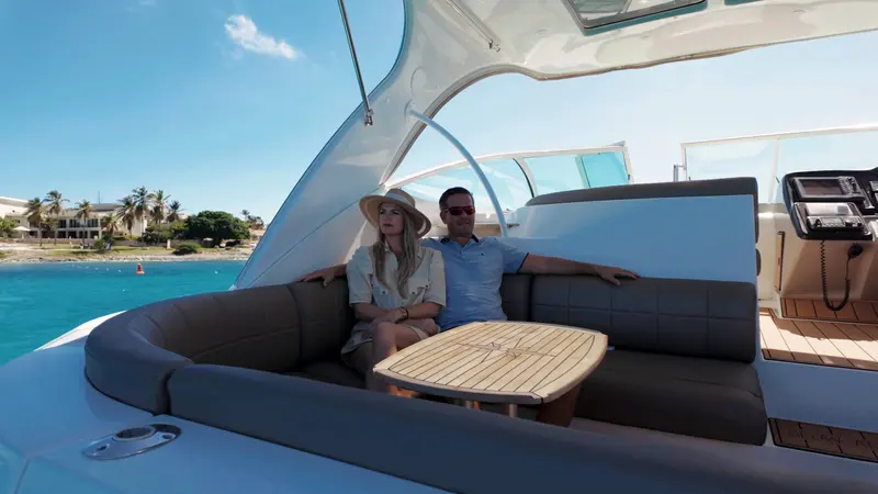 Couple relaxing in the cockpit lounge of Eden Luca Red at anchor, palm trees on the shore