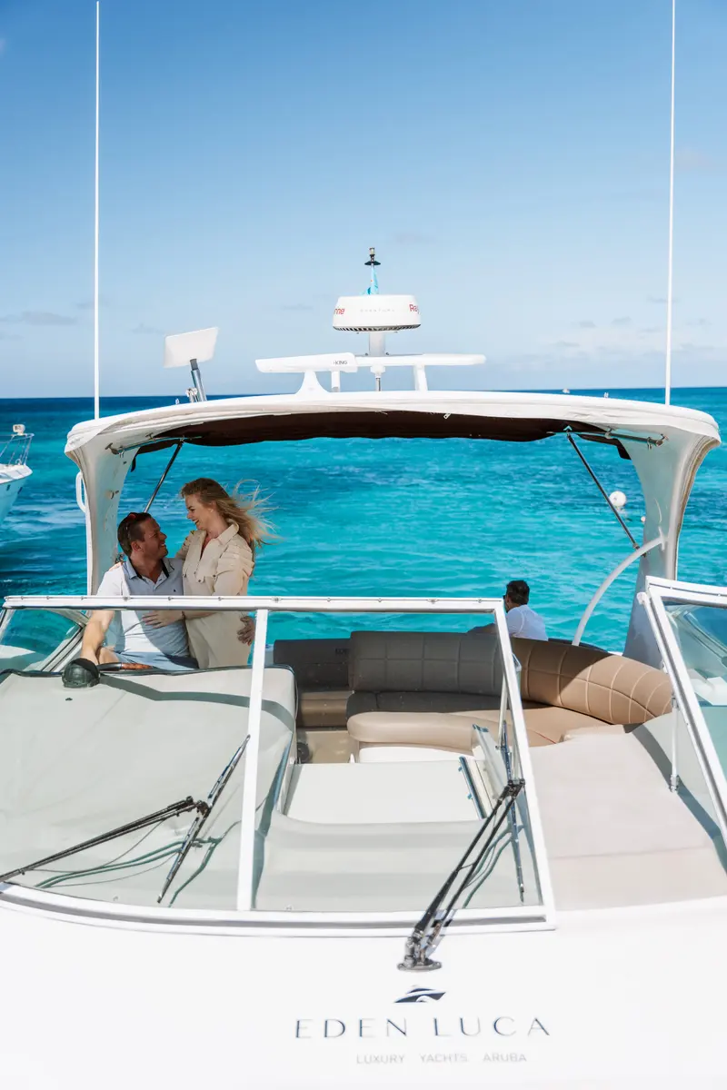 Couple embracing under the hardtop of Eden Luca Red, turquoise water and blue sky beyond