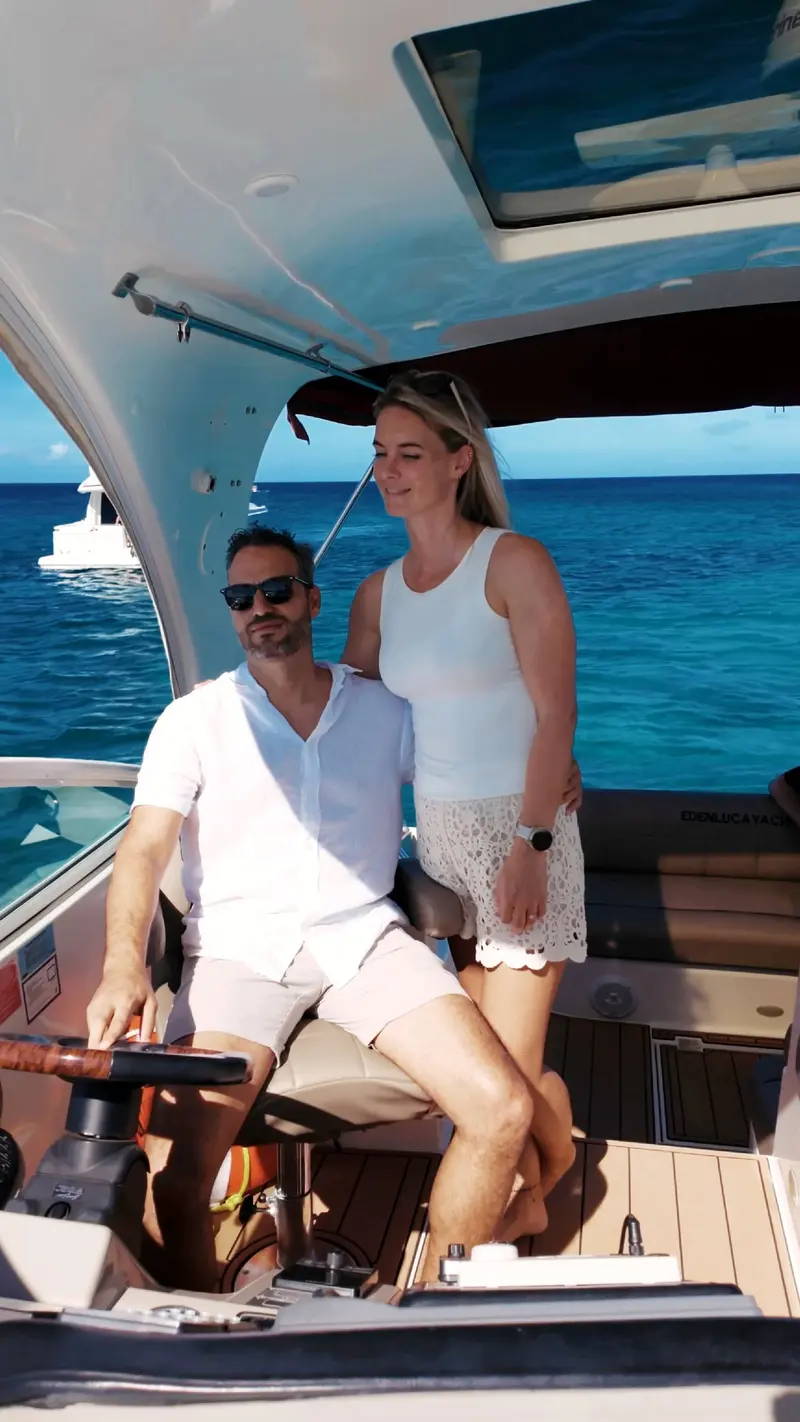 Couple smiling at the helm of Eden Luca Red under the hardtop, open sea beyond