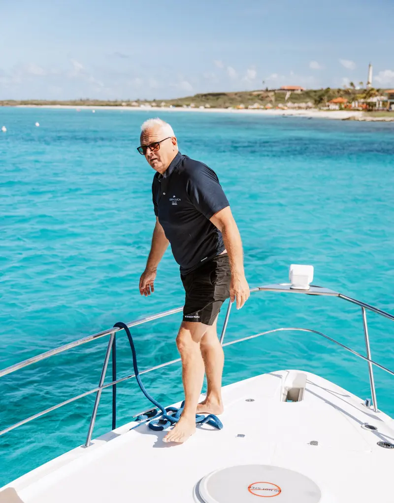 Eden Luca crew member handling the bow line, the turquoise Aruba shoreline behind