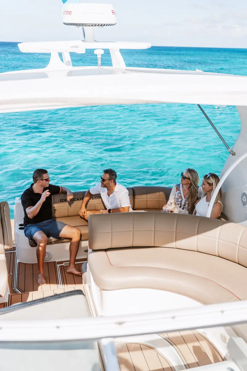 Two couples chatting over drinks in the cockpit of Eden Luca Red, turquoise water behind