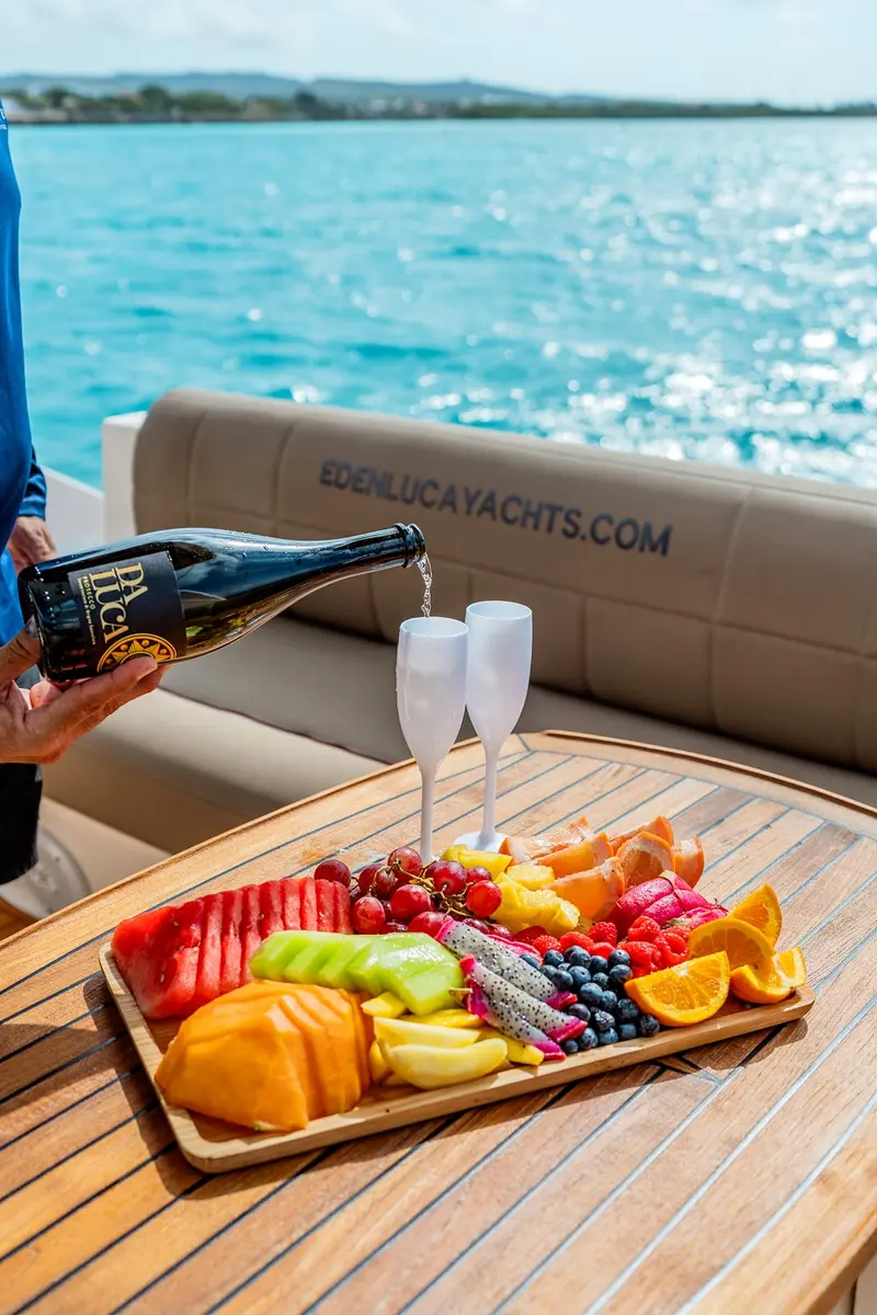 Bubbly poured beside a fresh fruit platter on the teak table; the fruit platter and champagne are optional upgrades