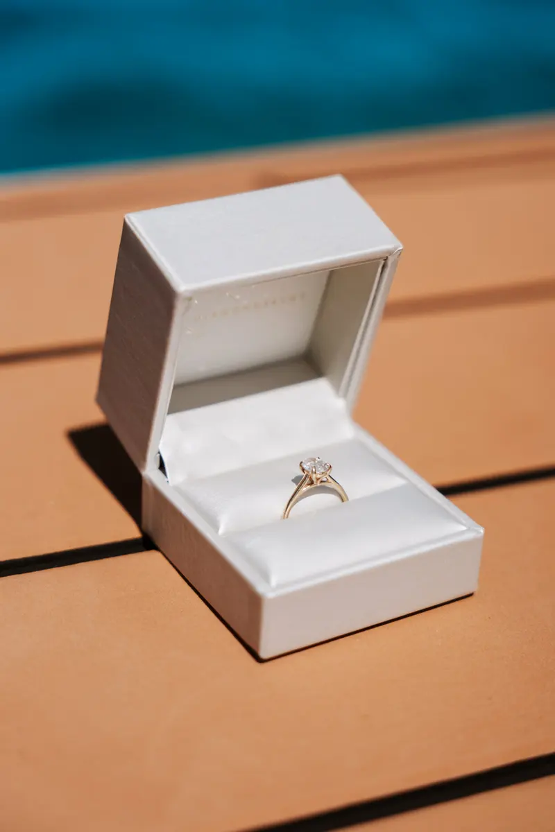 Open ring box with an engagement ring on the sun-warmed deck of an Eden Luca yacht