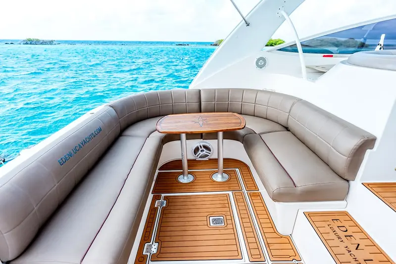 Cockpit lounge and teak table of Eden Luca Red seen from above, turquoise water alongside