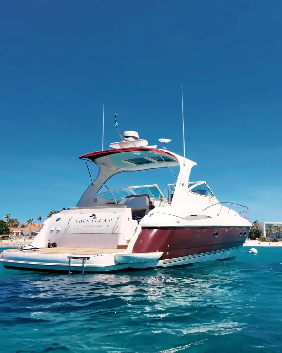 Eden Luca Red at anchor off a palm-lined Aruba beach in clear blue water