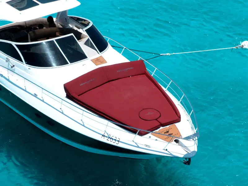 The bordeaux bow sun lounge of Eden Luca Red from above, one continuous cushion over the turquoise sea