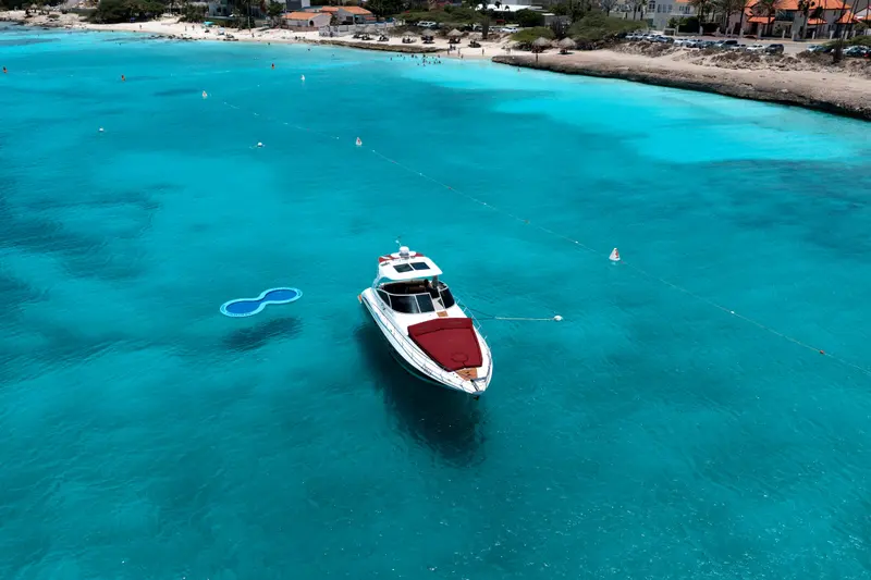 Eden Luca Red alone in a turquoise bay off Aruba, a quiet beach on the shore