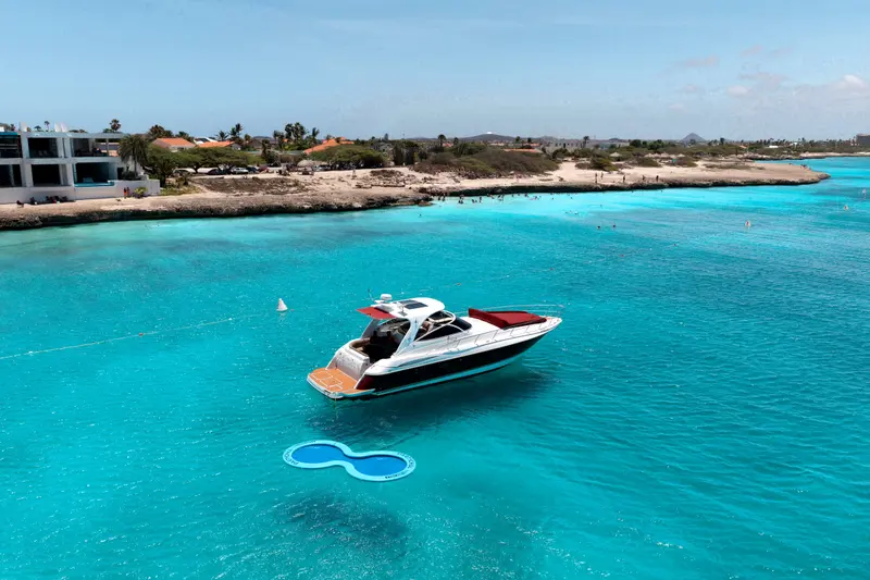 Eden Luca Red at anchor with the SunChill float, Aruba's coastline and turquoise shallows beyond