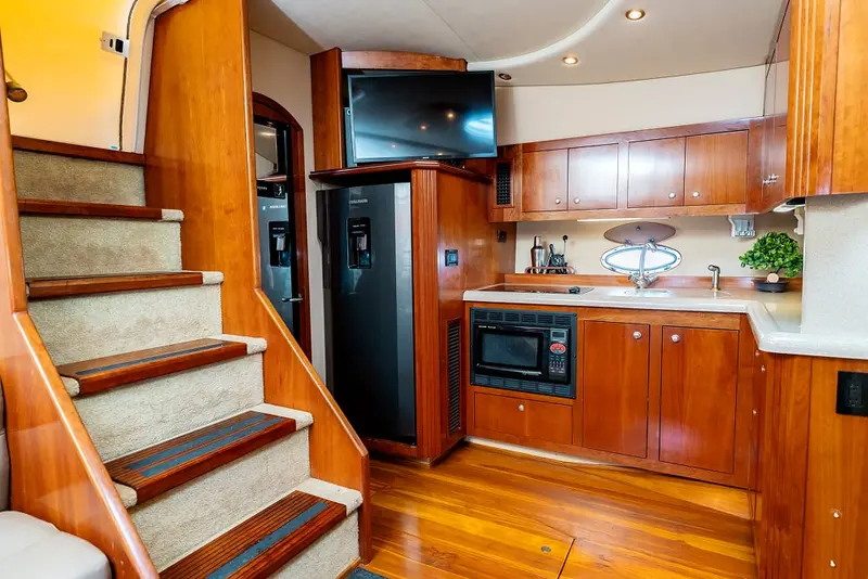 Below-deck galley of Eden Luca Red with cherry-wood cabinets, fridge and the stairs up to the cockpit