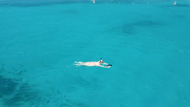 Drone view of a snorkeler floating in vivid turquoise water off Aruba