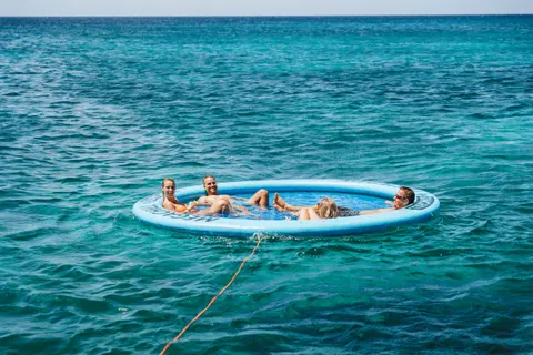Convidados relaxando juntos na boia SunChill em águas turquesa de Aruba