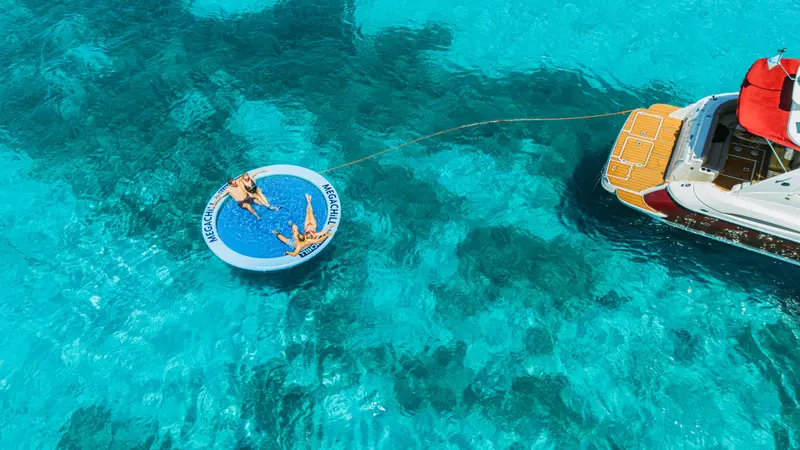 Drone view of guests on the SunChill float tethered behind Eden Luca Red in clear turquoise water