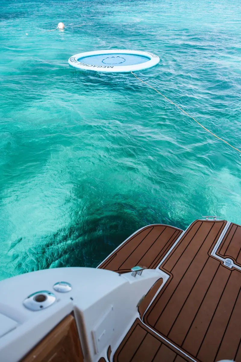 Teak swim platform over crystal-clear water, the SunChill float waiting just behind the yacht