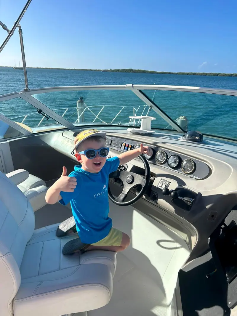 A young guest at the helm of an Eden Luca yacht giving a thumbs up: families welcome