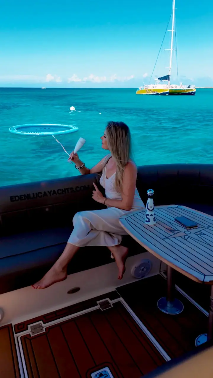 Guest raising a glass of bubbly on Eden Luca Red, the SunChill float and a catamaran behind