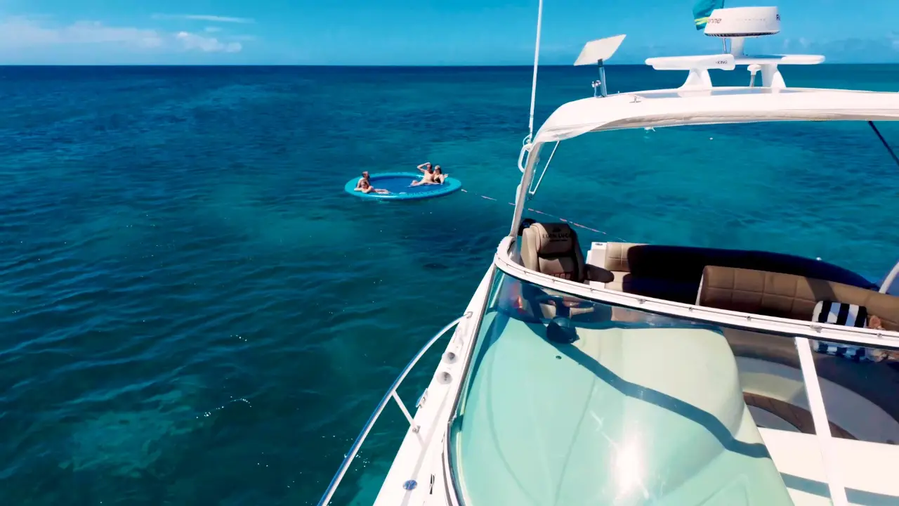 Guests on the SunChill float behind Eden Luca Red at anchor in clear turquoise water