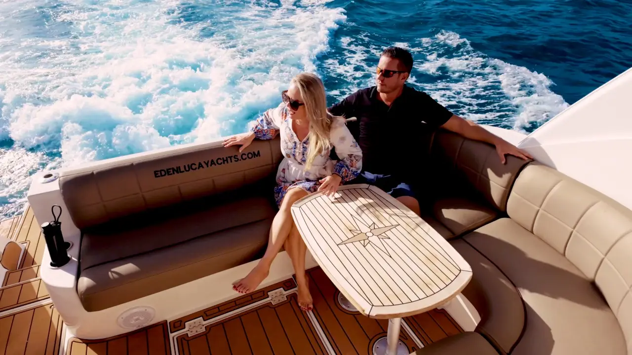 Drone view of a couple in the cockpit lounge of Eden Luca Red, the wake foaming behind