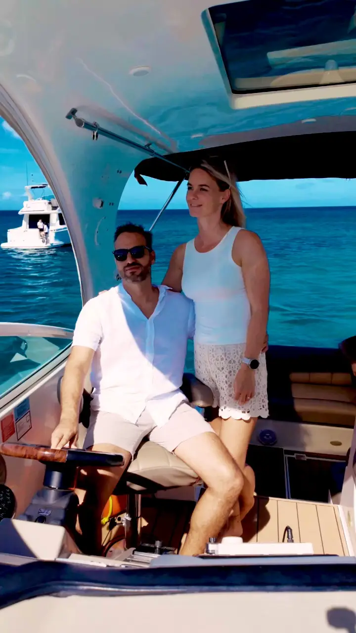 Couple at the helm of Eden Luca Red under the hardtop, open sea beyond