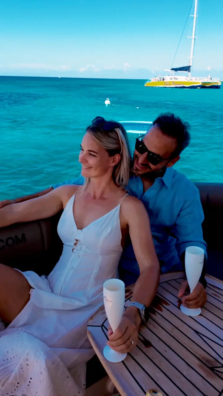 Couple relaxing in the cockpit lounge of Eden Luca Red, a private yacht charter at anchor in Aruba's turquoise water