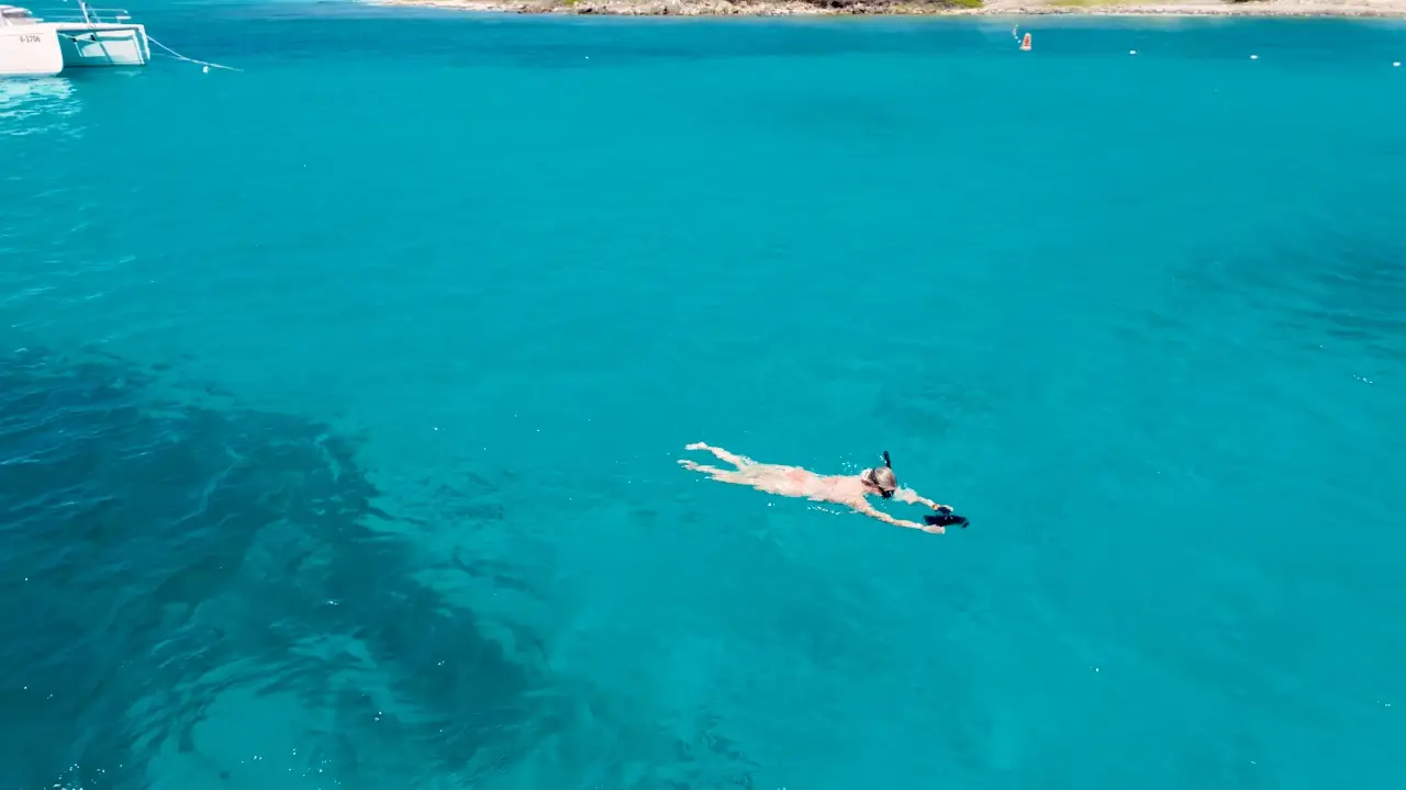 Drone view of a snorkeler gliding over clear turquoise water in Aruba
